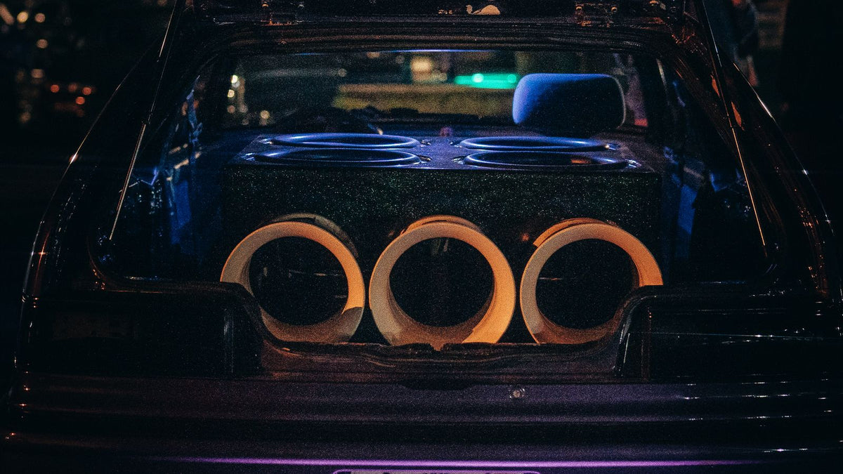 Car amplifier impedance and bridging India 2026 - multiple subwoofers mounted in a car boot enclosure at night, series and parallel wiring and amplifier protect mode