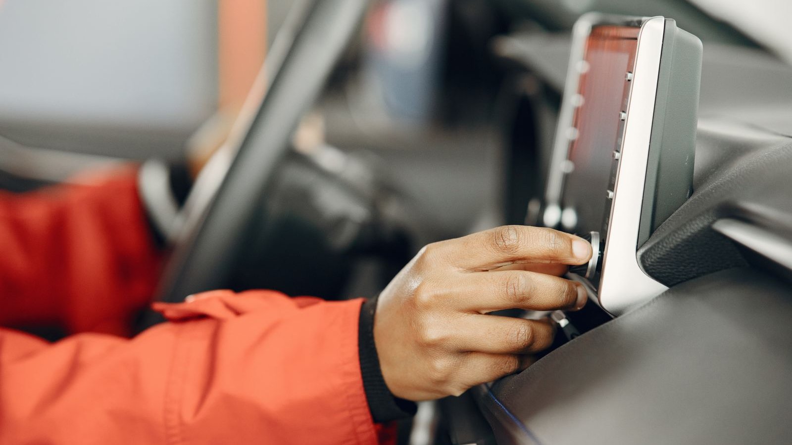 Hand adjusting a car stereo on the dashboard - why car speakers crackle buzz or distort and how to fix it by symptom, India 2026 troubleshooting guide