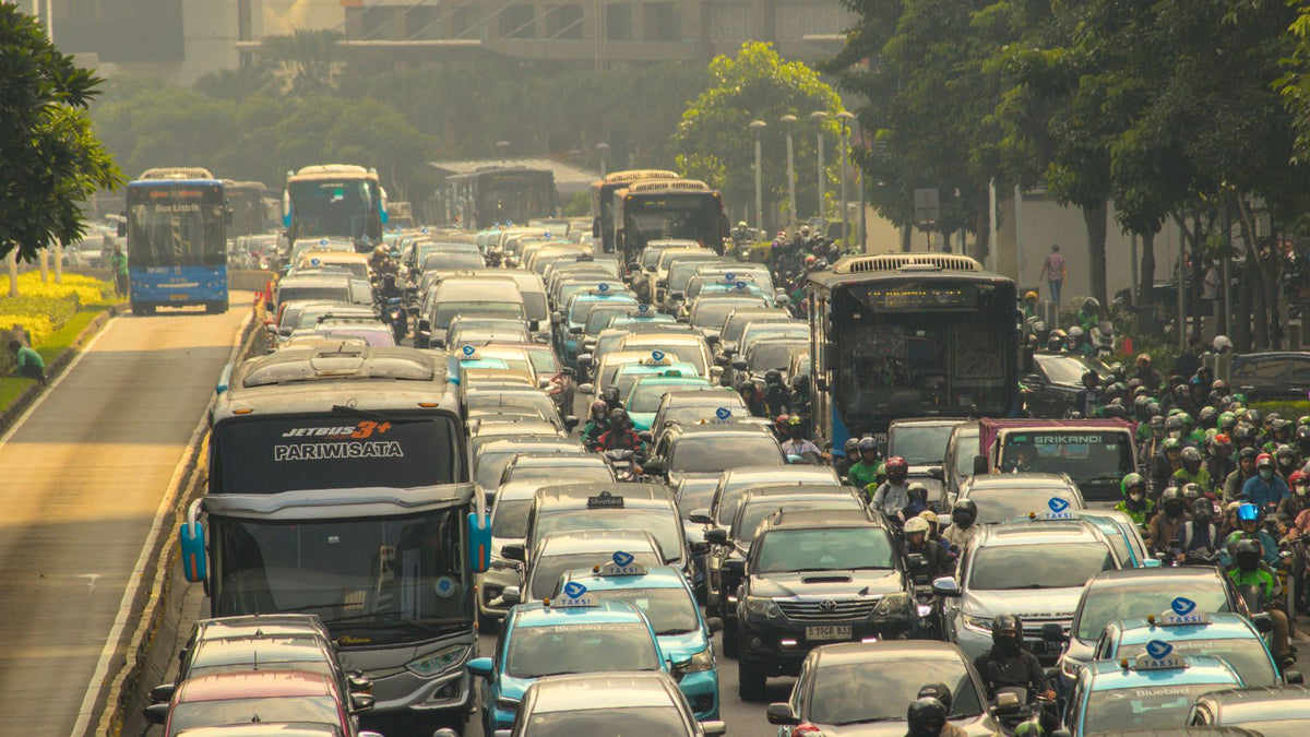 Car cabin air quality PM2.5 2026 - dense city traffic jam of buses cars and scooters in visible haze, in-vehicle pollution exposure and cabin filter limits