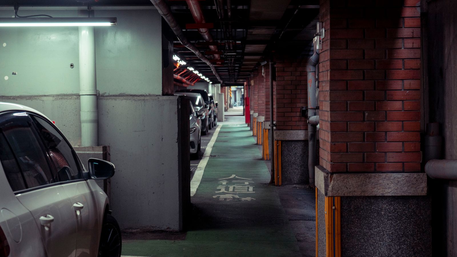 Parking sensors vs camera India 2026 - tight basement car park passage with concrete pillars, bollards and low kerbs, the obstacles ultrasonic sensors and cameras each miss